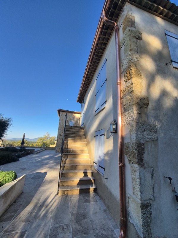 Descente pluviale en cuivre courant sur toute la hauteur d'une façade en pierre