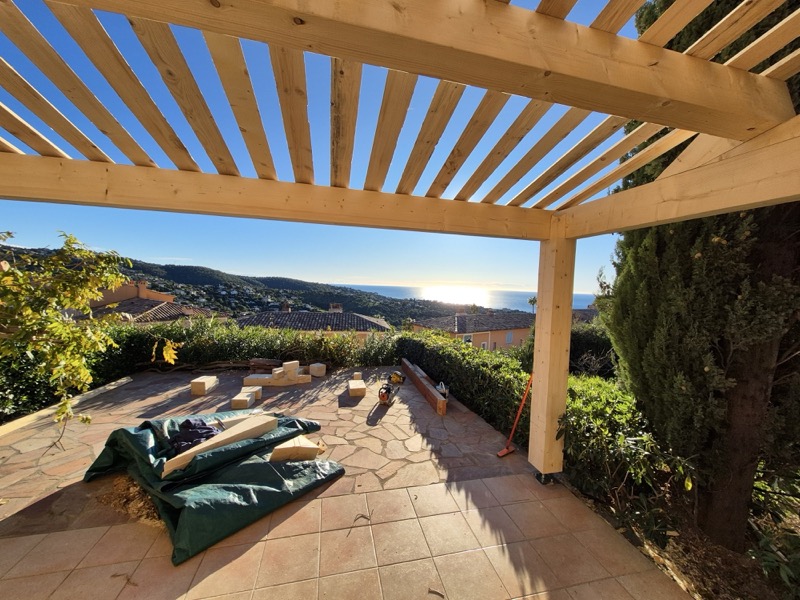 Structure neuve de pergola en bois contre-collé brut, poutres et chevrons assemblés