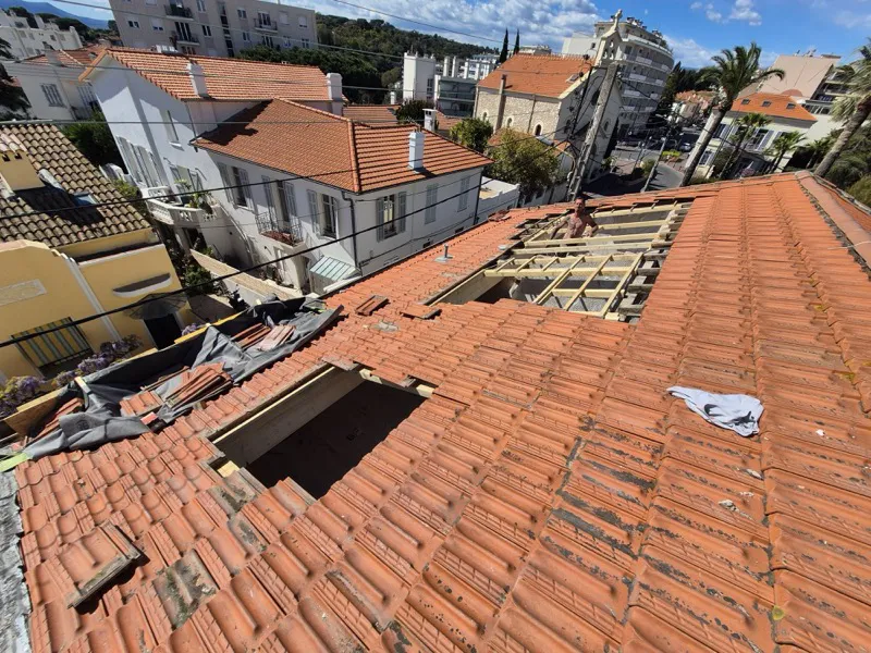 Deux ouvertures découpées dans un versant de toiture en tuiles à Cannes, chevrons apparents