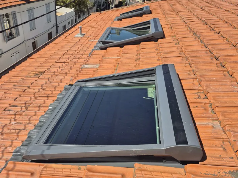 Trois fenêtres de toit Velux posées et ouvertes sur une toiture en tuiles à Cannes