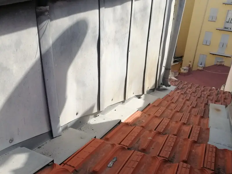 Pied d'un bardage en zinc à Nice, bavettes individuelles épousant le relief des tuiles