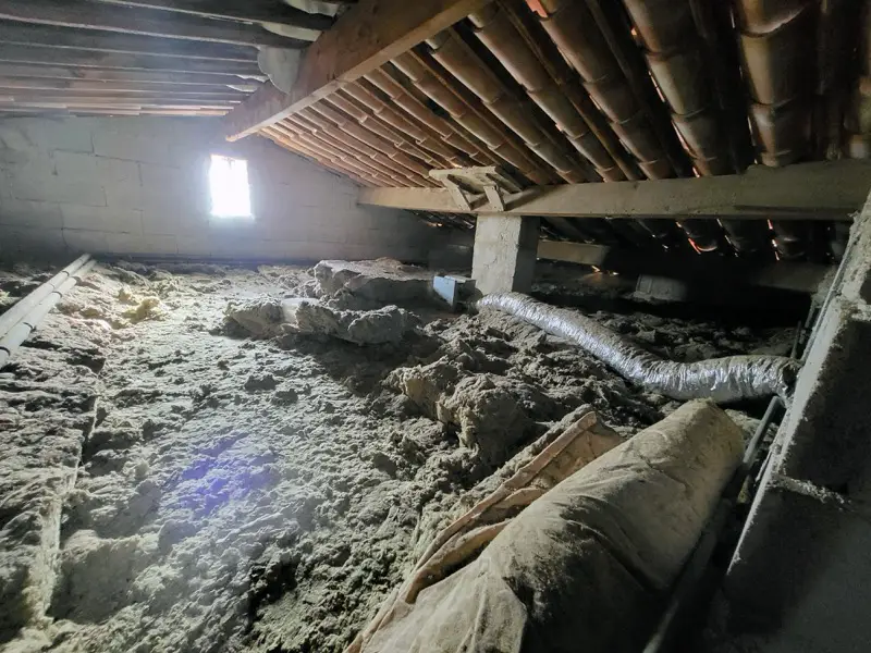 Combles avant nettoyage à Châteauneuf-de-Grasse, isolation en vrac vieillissante et gaines posées en travers