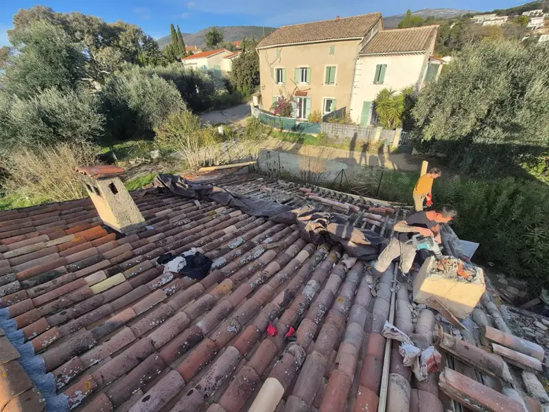 Dépose des tuiles canal anciennes engagée sur la toiture, cheminée maçonnée encore en place