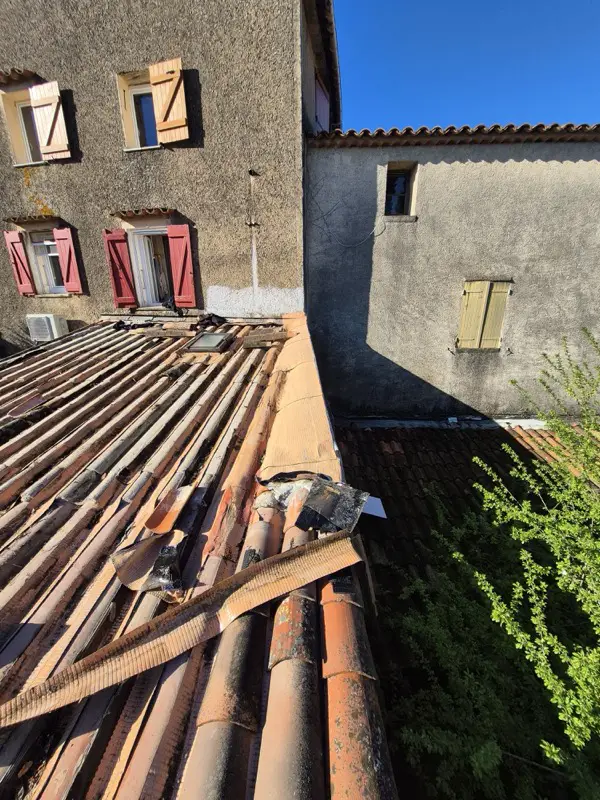 Toiture imbriquée entre les façades des maisons voisines à Saint-Paul-en-Forêt, dépose en cours