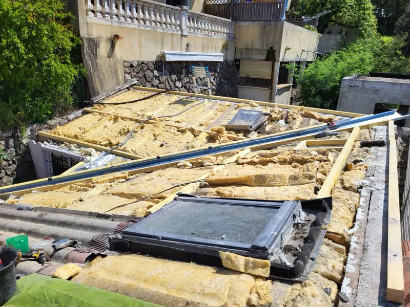 Toiture déposée à Vallauris, isolant à nu et bois de charpente apparents, maisons voisines en surplomb