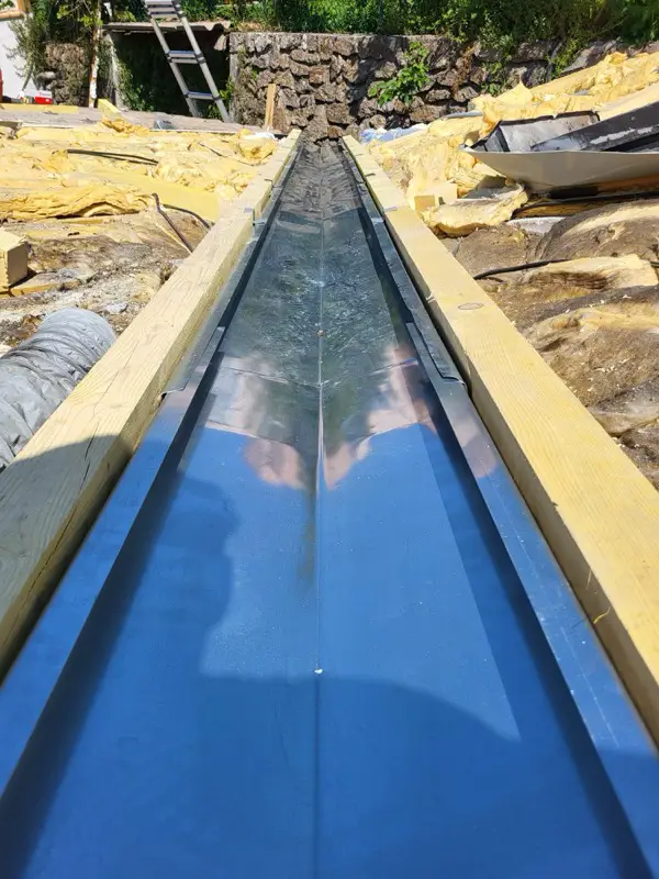 Chéneau métallique neuf soudé en continu entre les deux pans, mur de soutènement en arrière-plan