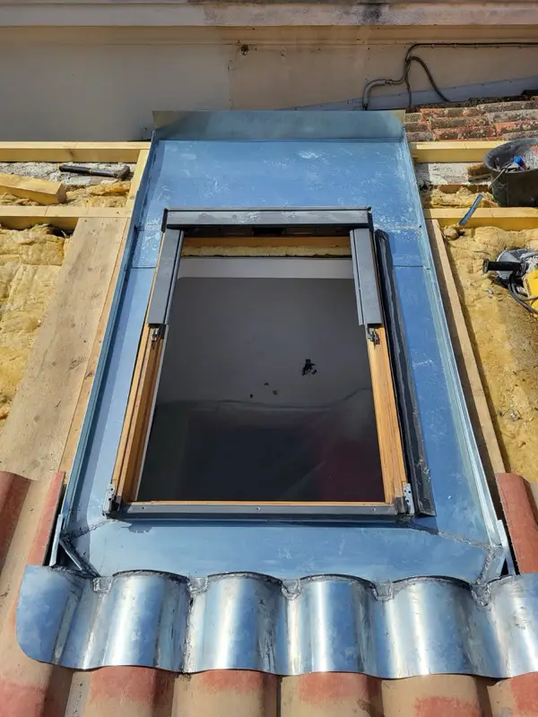 Abergement en zinc façonné sur mesure autour du Velux, bavette moulée sur le relief des plaques support de tuiles
