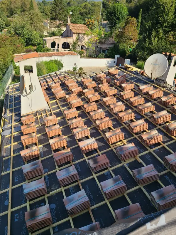 Écran de sous-toiture et liteaunage neufs sur une toiture d'Opio, tuiles réparties en piles avant la pose