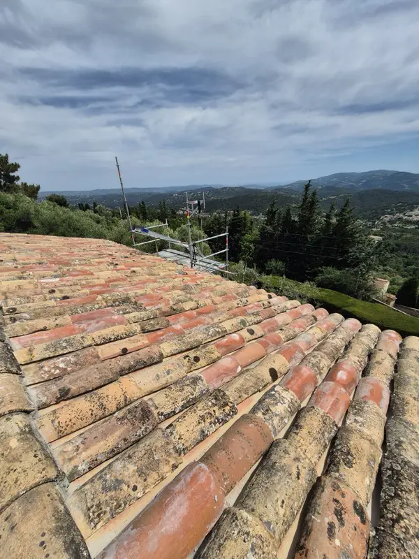 Tuiles canal anciennes patinées reposées sur la toiture, vue sur la vallée de la Siagne