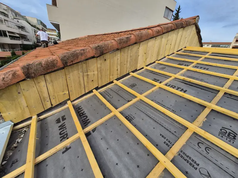 Jonction entre deux niveaux de toiture reconstruite en bois neuf sur un chantier de Fréjus